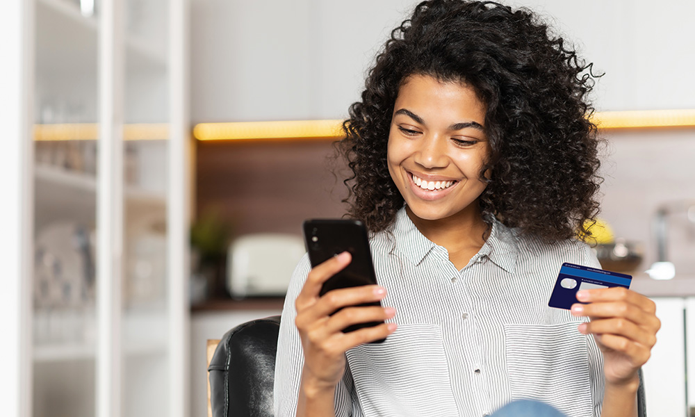 Teen girl smiling holding a phone and bank card