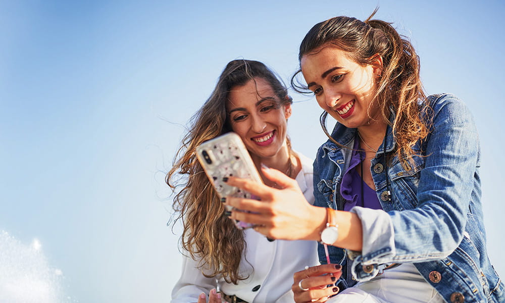 2 women outside looking at a mobile phone 