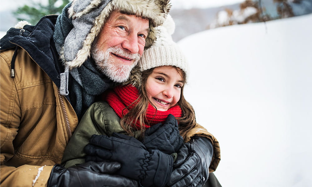 A grandfather and his granddaughter embracing in the snow