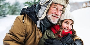 A grandfather and granddaughter playing in the snow
