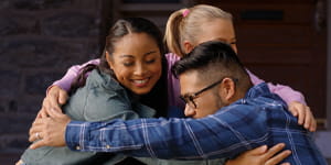 A family embracing on the front steps of their home
