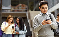 A student walking with his headphones and a mobile phone