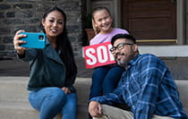 A family posing with a sold sign in front of a new home