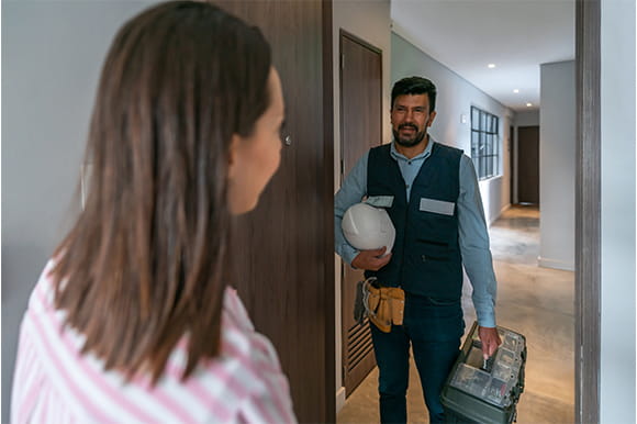 Man dressed as a contractor standing in the doorway talking to a homeowner