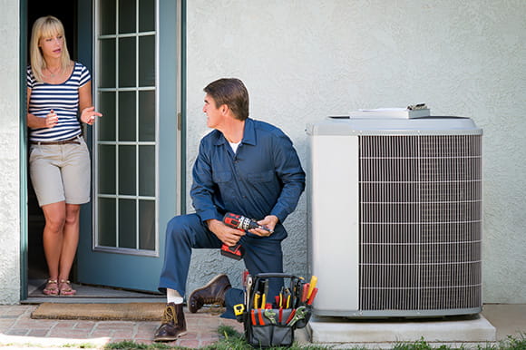A repair man working on an air conditioning unit
