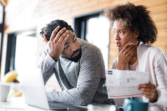 couple at the table looking at the laptop discusses debt