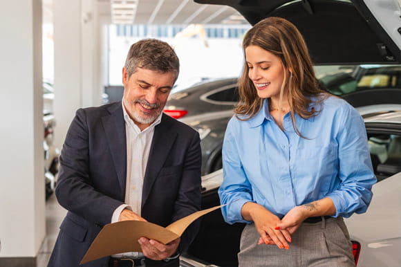 Man shows a woman with a blue shirt a folder. Is the extended car warranty worth it? 