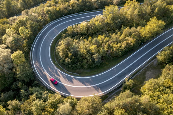 Aerial image of a red car on a very curvy road.
