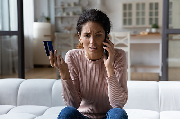 woman holding a bank card while on the phone