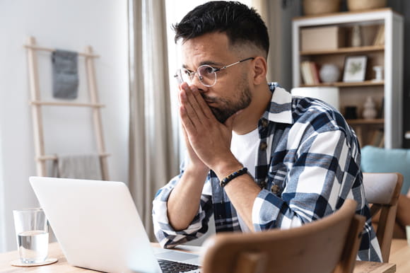 man with black and white checked pattern shirt is in deep thought about the cost of paying the minimum due